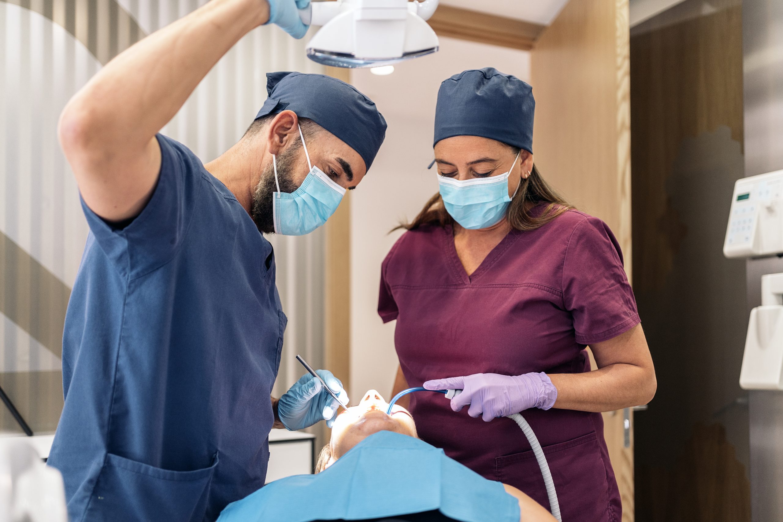 Stock photo of workers of a dental clinic wearing uniforms with a patient.