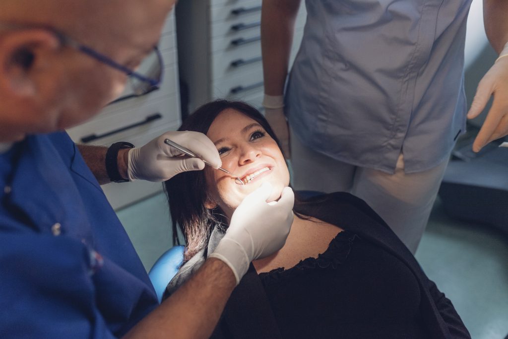 Dentist and dental nurse carrying out dental procedure on female patient