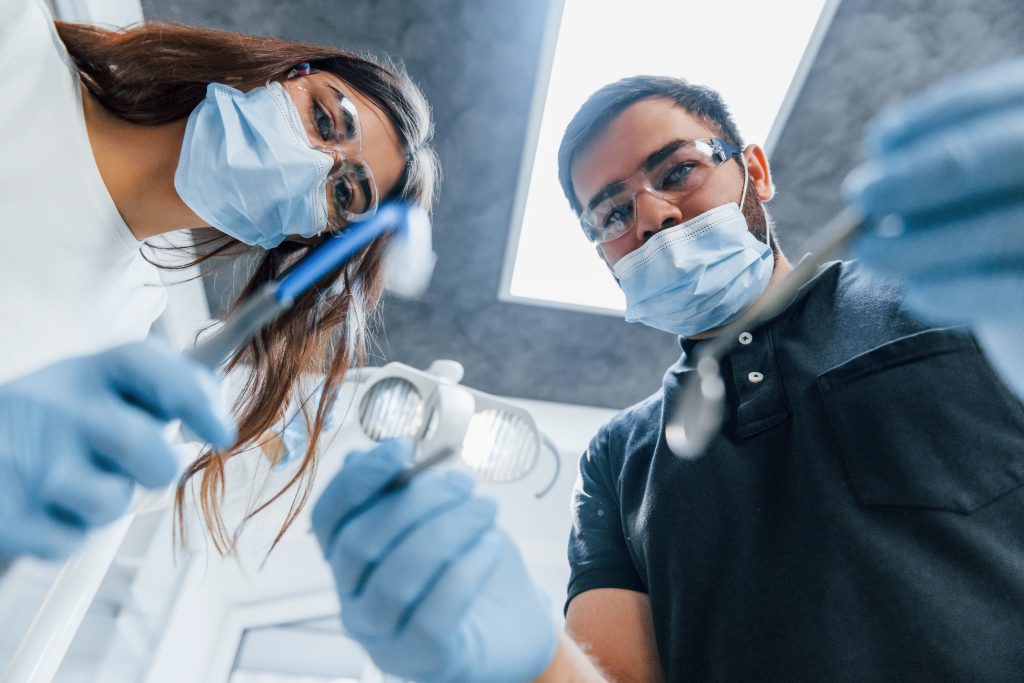Male and female dentists working in the office together. First person view.