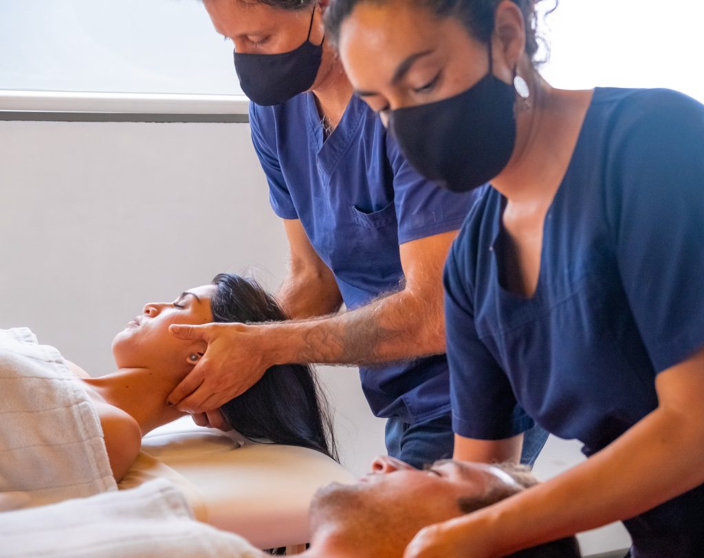 professional masseurs, doing treatments in a spa to a Latin couple. with protective covid masks