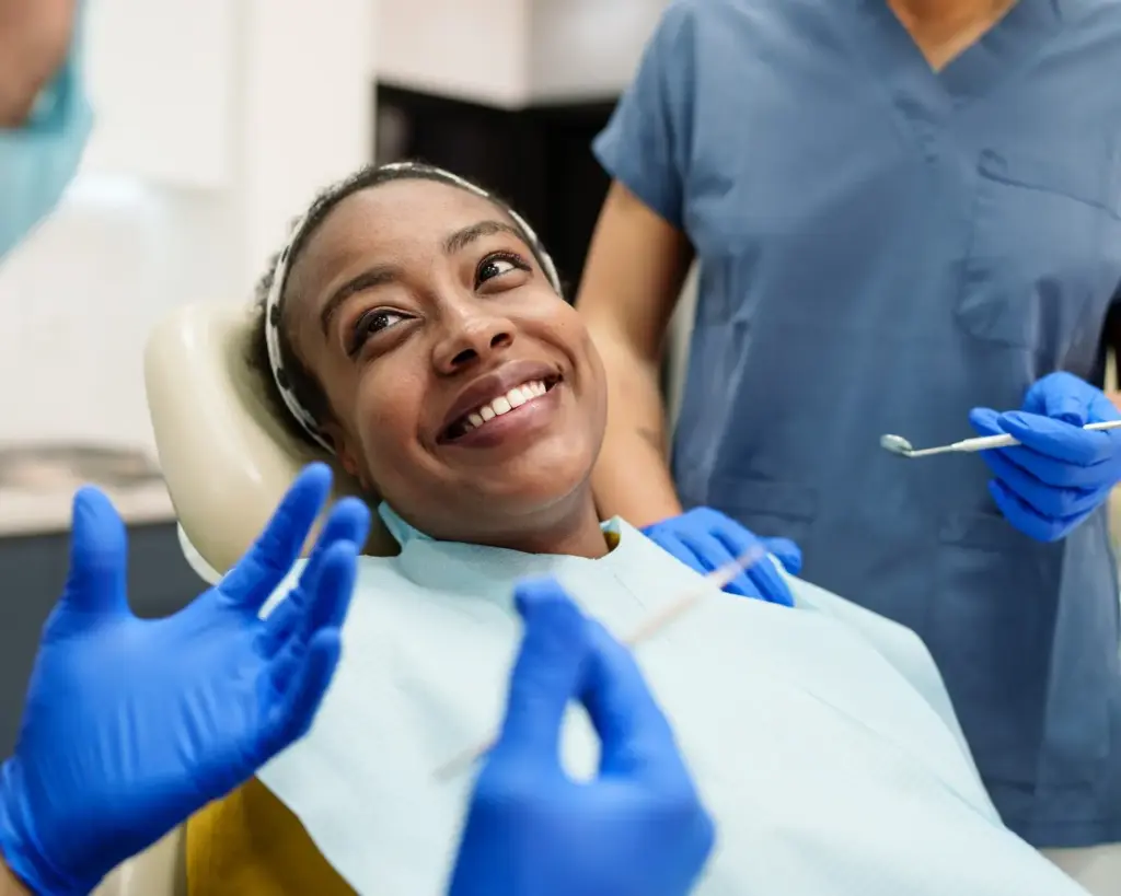 Patient lying in dental chair smiling while talking to a dentist